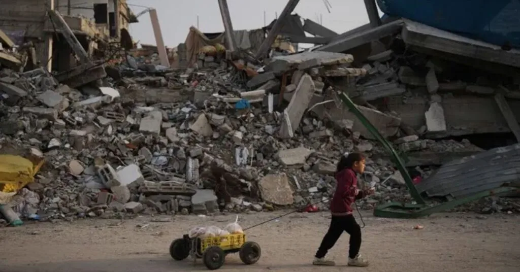 গাজা শহরে ধ্বংসস্তূপের পাশে দিয়ে হেঁটে যাচ্ছে একটি শিশু।